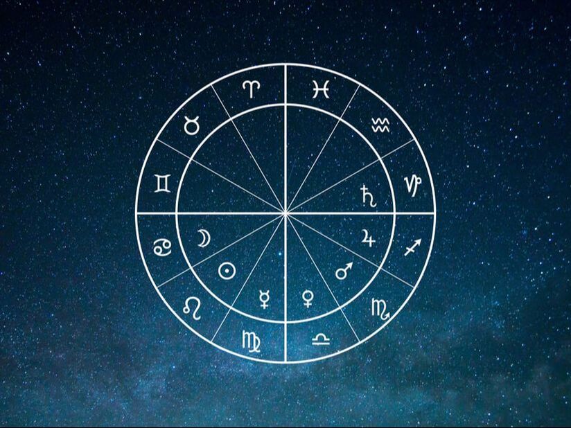 Fotografia do céu nocturno com as estrelas num fundo azul escuro. Ao centro uma mandala astrológica com os 12 signos do zodíaco e os 7 planetas tradicionais.